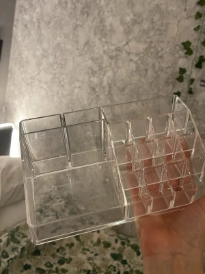 Transparent sminkorganiserare i akryl - Praktisk och stilren sminkorganiserare i genomskinlig akryl med flera fack i olika storlekar för förvaring av sminkborstar, läppstift och andra skönhetsverktyg. Perfekt för att hålla ordning på sminkbordet och snabbt hitta dina favoriter. 12 cm bred och höjd 7 cm