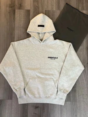 🩶🤍Light Oatmeal Essentials Hoodie🩶 🤍 - Säljer min hoodie helt oanvända Fear of God Essentials i färgen Light Oatmeal. Superfin ljus grå ton som passar till allt! Oversized passform och riktigt mjuk, tjock kvalitet – både trendig och tidlös.  Perfekt till vardags eller för en clean streetstyle-look ✨ Passar XS och S. Tar emot rimliga bud. Hör av dig vid frågor! 
