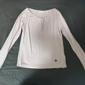 Ljusrosa långärmad topp - Ljuslila ribbad långärmad topp med rund hals och liten knytning framtill