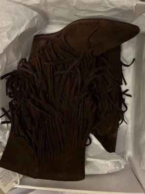 Bruna mocka boots med fransar - Säljer ett par bruna cowboy boots i mocka med långa fransar längs skaftet. Er semsket skinn! ny med lappen på! selger fra norge, så foretrekker vipps<3