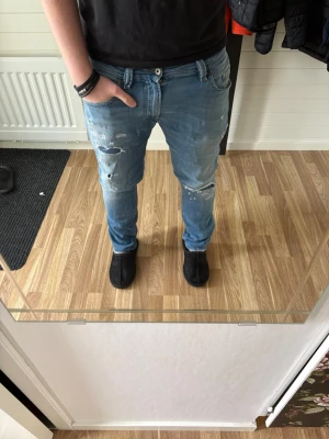 Diesel jeans - Säljer ett par ljusblå jeans med slitningar från diesel. Jeansen har en smal passform och klassisk femficksdesign. Perfekta för en avslappnad och trendig look. Materialet är denim i bomull och de har en snygg tvättad finish. På bild är jag 183cm! Vid frågor är det bara att ställa och pris kan diskuteras😁