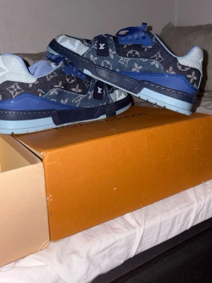 Louis Vuitton blå denim sneakers - Säljer ett par Louis Vuitton sneakers i blå denim med ikoniskt monogrammönster. Skorna har blå detaljer i mocka och läder, samt matchande blå skosnören och sula. Snygg och unik design som sticker ut i mängden.