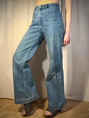 & OTHER STORIES, Blåa vida jeans med hög midja - Säljer ett par ljusblå & OTHER STORIES-jeans med hög midja och vida ben. Jeansen har stora fickor fram och bak samt markerade sömmar. Materialet är klassisk denim i bomull.