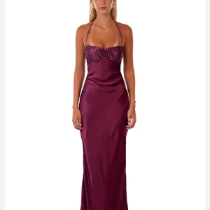 Balklänning från I AM DELILAH - Snygg vinröd långklänning i glansigt satinmaterial. Klänningen har tunna axelband, halterneck och en dekorativ detalj med paljetter över bysten. Figurnära passform. Perfekt till bal eller annat festligt tillfälle. Org pris är 2248kr, betalade 300kr frakt+ 280kr tull