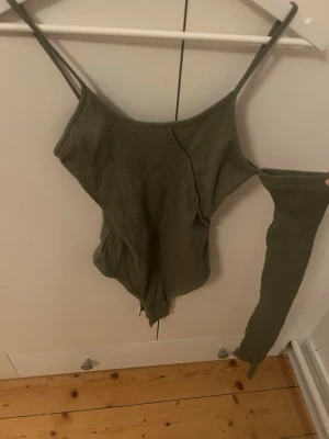 Grön ribbad one arm body - Ett grönt linne/body med en arm i strl S. Aldrig använd, prislapp finns kvar. 