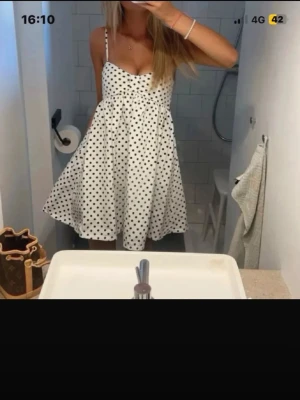 Prickig klänning zara - Söt vit klänning med svarta prickar och tunna axelband. Klänningen har en utställd kjol och en feminin, luftig passform som passar perfekt till varma dagar. Materialet känns lätt och bekvämt, och modellen har en klassisk, tidlös look.