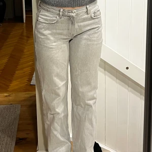 Ljusgrå raka jeans med medel hög midja  - Säljer ett par ljusgrå jeans från Gina tricot med rak passform och klassisk femficksdesign. Jeansen har normal midja och är tillverkade i ett mjukt denimtyg. Perfekta för en avslappnad och trendig look.