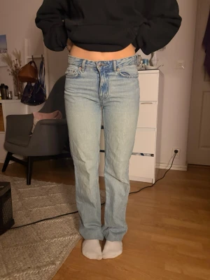 Ljusblå raka jeans med hög midja - Säljer ett par ljusblå jeans med rak passform och hög midja. Klassisk femficksmodell och snygg tvätt som ger en avslappnad vibe. Jeansen har bälteshällor och knappgylf. Perfekta till en casual look.