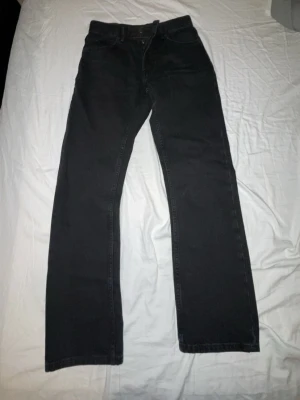 Svarta raka jeans - Säljer ett par svarta jeans med rak passform och klassisk femficksdesign. Jeansen har normal midja och stängs med knapp och dragkedja. Perfekta för dig som gillar en enkel och stilren look.