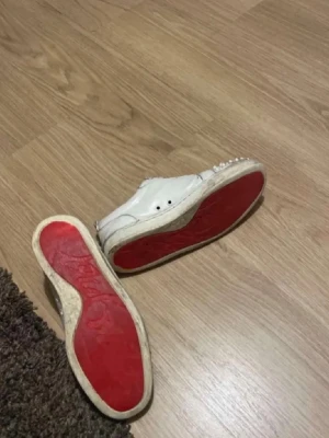 Christian Louboutin skor - Här säljer jag ett par äkta skor ifrån Christian Louboutin. De är en känd modell med spikar och den klassiska vita färgen med röd sula under! Dessa garanterar jag äktahet, men de är i ett sämre skick pga lång användning. Hör av dig vid prisförslag, är rörlig 