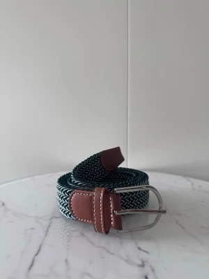 Grön vitt flätat bälte - Tja det är helt nytt och är ca 105cm långt och 3,5cm brett. Det är i elastiskt material och en massa andra färger finns i min profil.