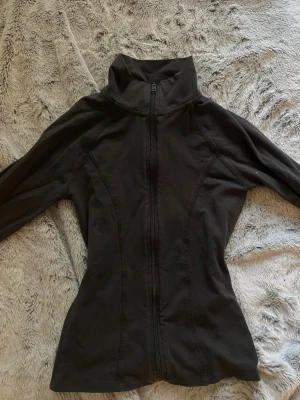 Mörkgrå ziptröja från Gina Tricot - Träningsjacka ifrån Gina tricot, köptes för ca 1 år sen och den har bara legat i garderoben, använd max 10 gånger, vill bli av med den så därav priset! Den är mörkgrå men ser svart ut i ljuset, skriv privat om ni vill ha mer bilder!🥰