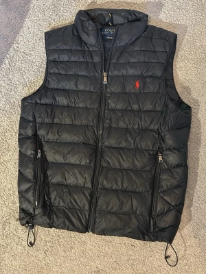 Polo Ralph Lauren Väst - En riktigt schysst och fräsch Ralph Lauren Väst i en snygg mörkblå färg med röd logga på bröstet. Västen är i toppskick med absolut 0 defekter. Har haft den själv i drygt ett år och hållt den i dunder skick. Storlek S, modellen på bilden är ungefär 183 men skulle säga att den sitter lite bättre på någon strax kortare. Hör gärna av er med eventuella bud eller frågor😊