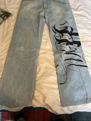 Baggy jeans - Riktigt skjyssta baggy jeans med ett coolt tryck på ena benet. Bra kvalitet och ger dig en snygg 90tals look. Passformen är även den ruggigt bra! Skriv för mer bilder!