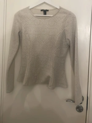 Beige långärmad topp Forever 21 - Snygg beige långärmad topp från Forever 21 med subtilt mönster i tyget. Toppen har rund halsringning och figurnära passform som framhäver siluetten. Perfekt att styla med jeans eller kjol för en trendig look.