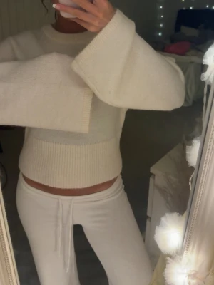 Vit stickad tröja från Gina Tricot - Mysig vit stickad tröja från Gina Tricot med breda ärmar och ribbstickade detaljer vid ärmslut och midja. Tröjan har en något croppad passform och är perfekt för lager-på-lager-stil. Enkel att matcha med både jeans och mjukisbyxor.