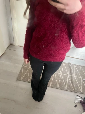 Mörkröd fluffig tröja - Mysig mörkröd fluffig tröja med rund hals och långa ärmar. Tröjan har en avslappnad passform och är gjord i ett mjukt, lurvigt material som känns skönt mot huden. Perfekt för dig som gillar en enkel men ändå trendig look.