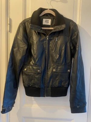 Svart skinnjacka från Vero Moda - Snygg svart skinnjacka från Vero Moda i storlek M med ribbad krage. Super snygg verkligen, men tyvärr har armarna slitits lite på ( som visas på bilderna ) så därför säljs den för billigare pris.💕