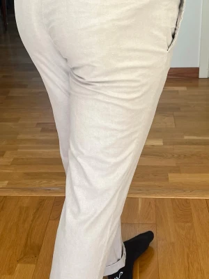 Beige chinos med rak passform - Snygga beige chinos med rak passform och klassiska fickor i sidan. Byxorna har bälteshällor och kan vikas upp nertill för en mer avslappnad look. Perfekta för dig som vill ha en stilren och enkel byxa till vardags. Materialet känns mjukt och bekvämt.