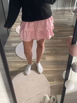 Rosa blommig volangkjol - Söt kort kjol i ljusrosa med små blommor och volangdetaljer. 