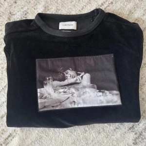 Svart velourtröja Limitato med tryck - Svart långärmad velourtröja från Limitato med ett stort svartvitt fototryck på bröstet. Tröjan har rund halsringning och en mjuk, lyxig känsla. Perfekt för dig som gillar unika prints och stilrena plagg.