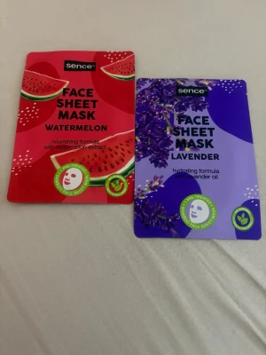 Sence Face Sheet Mask duo - Två ansiktsmasker från Sence: en Watermelon Face Sheet Mask med vattenmelonextrakt och en Lavender Face Sheet Mask med lavendelolja. Watermelon-masken har röd förpackning och lavendelmasken lila. Båda är engångsmasker i arkmaterial och veganska.