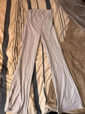 Grå mjukisbyxor från Gina Tricot - Superbekväma grå mjukisbyxor från Gina Tricot med hög midja och utsvängda ben. Tillverkade i mjukt och stretchigt material som passar perfekt för en avslappnad stil. Snygga att matcha med en crop top eller hoodie.