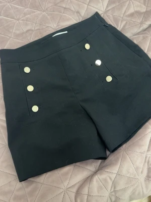 Svarta shorts med guldknappar - Stilrena svarta shorts med guldknappar framtill. 