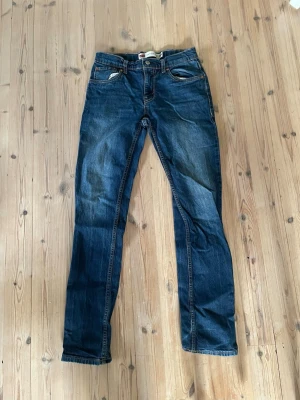 Mörkblå Levi's 512 slim taper jeans - Snygga mörkblå jeans från Levi's med klassisk femficksdesign och raka ben. Jeansen har en diskret tvättad look och detaljer som synliga sömmar och läderpatch bak i midjan. Perfekta för en avslappnad och trendig stil.