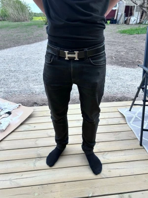 Svarta lean dean jeans herr - Snygga svarta lean dean jeans med klassisk femficksdesign och smal passform. Jeansen har tydliga sömmar och sitter tajt längs benen för en modern look. Perfekta för dig som gillar stilrena och enkla jeans i svart.