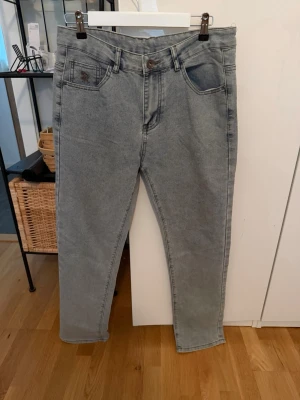 Gråa raka jeans från Replay - Snygga gråa jeans från Replay med raka ben och klassisk femficksdesign. Jeansen har en broderad logga på bakfickan och patch med Replay-märke i midjan. Tillverkade i denim med en lätt tvättad look som ger en cool vibe.