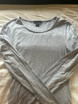 Grå långärmad topp från Amisu/ New yorker - En enkel och stilren grå långärmad topp från Amisu. Toppen har rund halsringning och är tillverkad i ett mjukt bomullsmaterial. Perfekt att matcha med jeans eller kjol för en clean look.