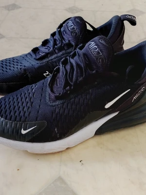 Nike Air Max 270 svarta sneakers - Nike Air Max 270 sneakers i svart mesh med vita detaljer och synlig Air Max-dämpning i hälen. Snygg sportig design med tydlig logga på sidan och tungan. Perfekta för en streetwear-look och riktigt bekväma att gå i. Storlek 41.  Bra skick.