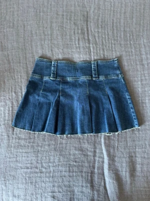Lågmidjad plisserad jeanskjol  - Säljer den här lågmidjade plisserade jeanskjolen. Den finns inte att köpa längre och är unik och snygg samt så sitter den väldigt skönt. Materialet är mer mjukt och bekvämt. 
