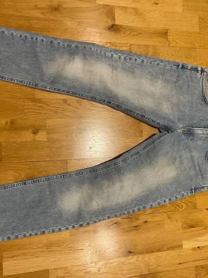Lee Ljusblå raka jeans med slitningar stl W30 L34 - Säljer ett par ljusblå jeans med raka ben och snygga slitningar på både fram- och baksida. Jeansen har klassisk femficksmodell och är tillverkade i denim. Perfekta för en avslappnad och trendig look.
