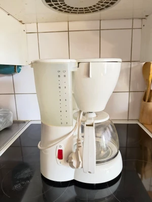 Vit kaffemaskin Melitta CafeLine - Säljer en vit kaffemaskin från Melitta, modell CafeLine. Bryggaren har en genomskinlig vattenbehållare med måttskala och en glaskanna med vitt handtag. Enkel design med röd strömbrytare och plats för filter. Perfekt för köket!