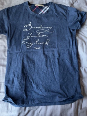 Blå Burberry t-shirt  - Säljer denna blåa burberry T-shirt då den har blivit för liten för mig. Tröjan är i storlek L men sitter mer som S/XS väldigt små i storleken 
