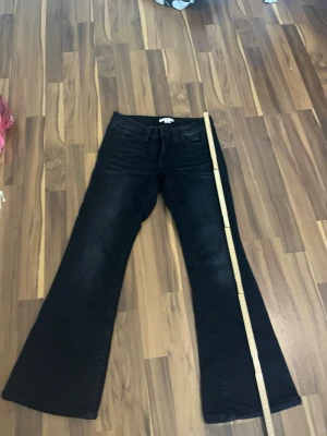 Svarta bootcut jeans med utsvängda ben - Snygga svarta jeans med bootcut-modell och utsvängda ben. Klassisk femficksdesign och hällor för bälte. Jeansen har en mörk tvätt och är perfekta för en trendig look. Materialet är denim med lite stretch för extra komfort.