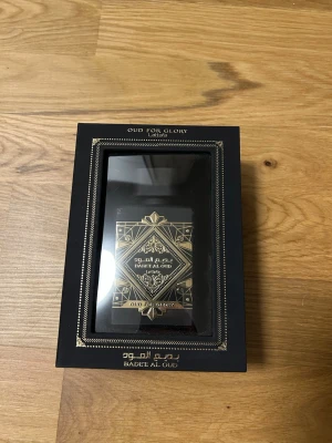 Badee Al Oud Oud For Glory parfym - Exklusiv parfym från Lattafa, Badee Al Oud Oud For Glory. Flaskan är matt svart med detaljer i guld och orientaliskt mönster. Kommer i en lyxig svart presentförpackning med gulddetaljer. Doften har tydliga oud-noter och ger en elegant känsla. Cirka 65-70 ml kvar i den.