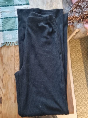 Svarta ribbade leggings - Svarta leggings med ribbad struktur och hög midja. Mjukt och stretchigt material som sitter skönt på kroppen. Perfekta att styla med oversized tröjor eller hoodies. Inga synliga loggor eller märken.