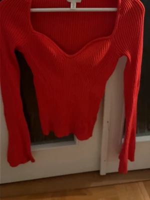 Röd ribbad topp från H&M - Trendig röd ribbad topp från H&M med lång ärm och snygg v-ringad formad halsringning. Toppen är figurnära och har en cool struktur som ger extra edge till din outfit. Storlek M men passar S lika bra. 