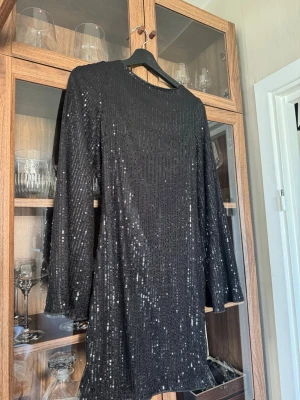 Svart glittrig paljettklänning - Snygg svart kortklänning täckt med glittrande paljetter. Klänningen har lång öppnare ärmar och rak passform, perfekt för dig som vill sticka ut. Öppen rygg och sitter jätte fint. Aldrig använt pågrund av att den var lite för kort för min smak. Tror jag köpte den på tiktok shop för 399kr🫶🏼