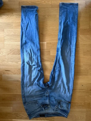 Blå raka jeans i bomull - Säljer ett par klassiska blå jeans med rak passform. Jeansen har fem fickor, bälteshällor och en snygg tvättad look. Tillverkade i bomull för en bekväm känsla och slitstark kvalitet. Perfekta till vardagsstilen! *bilderna blev upp och ner på nått sätt*
