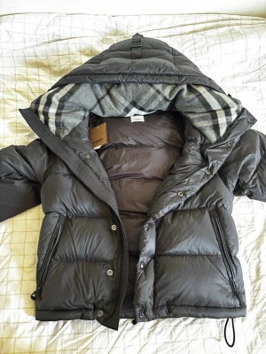 Svart Burberry jacka/väst - Snygg svart Burberry jacka som även blir till en väst när dragkedjorna på armarna dras av, väldigt bra till sommaren att ha som väst sedan när det börjar bli kallt så kan man alltid sätta på armarna igen!