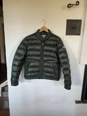 Mörkgrön dunjacka från Moncler - Otroligt snygg och sällsynt Moncler acorus jacka i färgen mörkgrön. Jackan har två dragkedjeförsedda fickor framtill och en diskret Moncler-logga på ärmen. Perfekt för vårkvällarna. Jackan är i väldigt fint skick men saknar en knapp vid kragen, går att fixa ny för 50kr. Skick 8/10. Självklart äkta. Vid frågor och funderingar, bara att höra av sig☺️