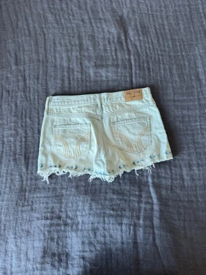 Ljusblå jeansshorts från Hollister - Jätte snygga ljusblå jeansshorts från Hollister.  Om man vill ha de mer mid så är de S men om man vill ha de mer lösa och lågmidjade så är de XS. Shortsen har fina och unika detaljer ner till och en jätte fin färg inför sommaren!