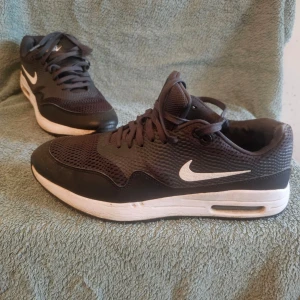 Nike Air Max svartvita sneakers - Svarta och vita Nike Air Max sneakers med klassisk swoosh-logga på sidan och AIR-tryck bak. Ovandelen är i mesh och syntetmaterial för bra andning och komfort. Sulan är vit med synlig Air-enhet för extra dämpning. Snygg och sportig design.