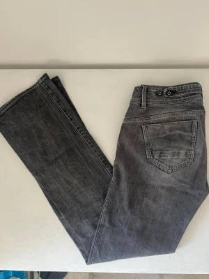 Lågmidjade bootcut - Säljer dessa jättefina bootcutjeans från G-Star, ljusgrå i väldigt bra skick! 39 cm midjemått och 83 cm innerbenslängd 