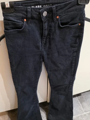 Svarta Peachy Flare jeans XS - Snygga svarta flare jeans från Peachy i storlek XS. Modellen har utsvängda ben och klassisk femficksdesign. Perfekta för dig som gillar en trendig och bekväm look. Jeans i stretchigt material som sitter tajt upptill och släpper ut vid vaden.