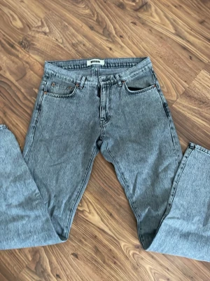 Grå raka jeans från Woodbird - Snygga grå jeans från Woodbird med klassisk femficksmodell och raka ben. Jeansen har en cool tvättad look och är tillverkade i denim. Perfekta för en avslappnad och trendig stil. Storlek 30W och 34L.